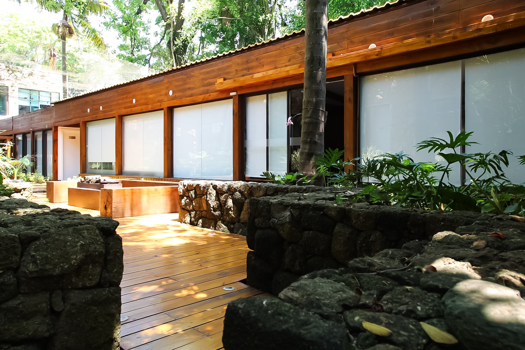 Fachada e entrada da clínica, em arquitetura de madeira e pedra integrada ao jardim